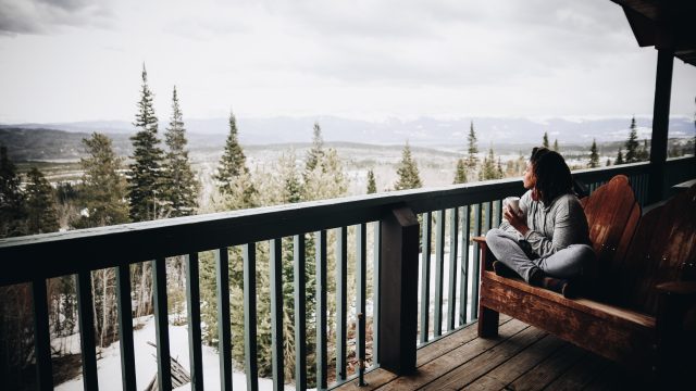 Woman Sitting Outside on Bench Enjoying Snowy View