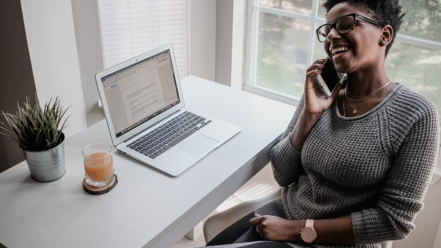 Woman Laughing While on Phone In Home Office